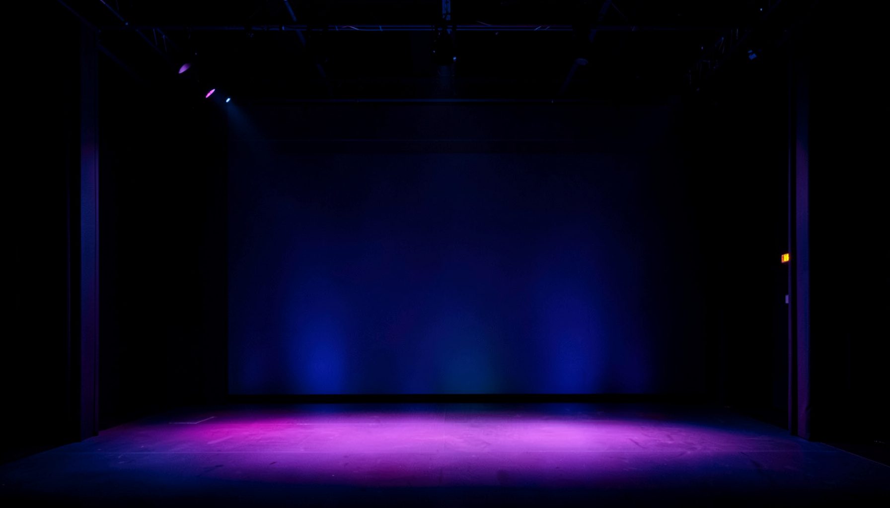 Abstract dark backdrop with subtle conference-stage lighting in deep blue and magenta